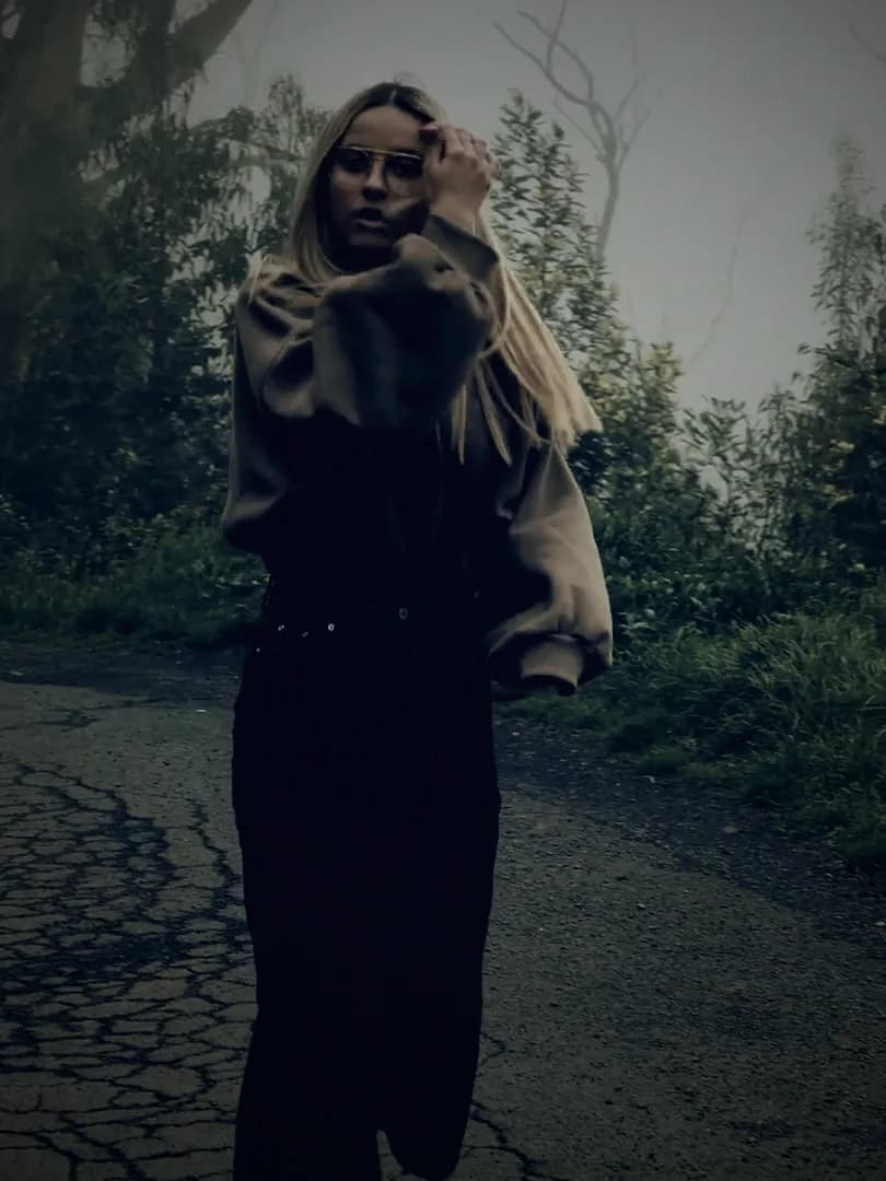 A young woman on a foggy roadside, graded in the series' blue.