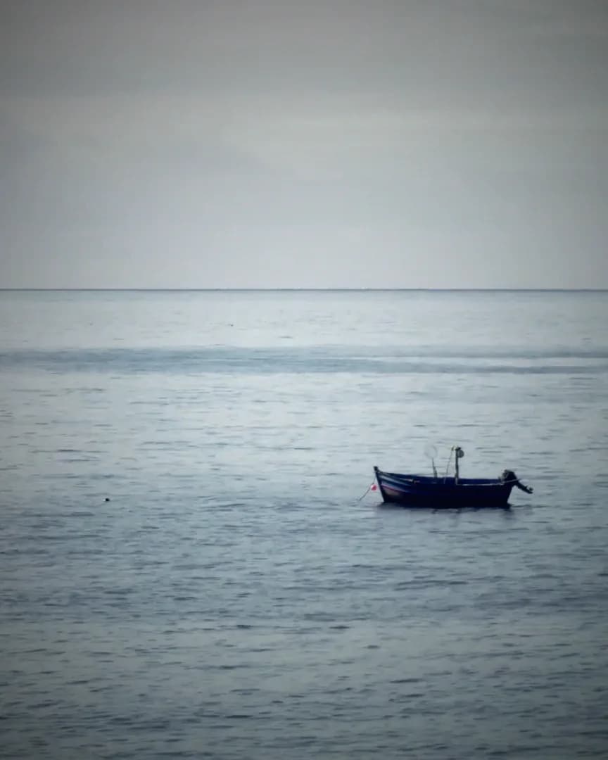 A single small boat on a calm, empty sea.